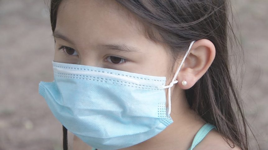 A kid is wearing a white mask