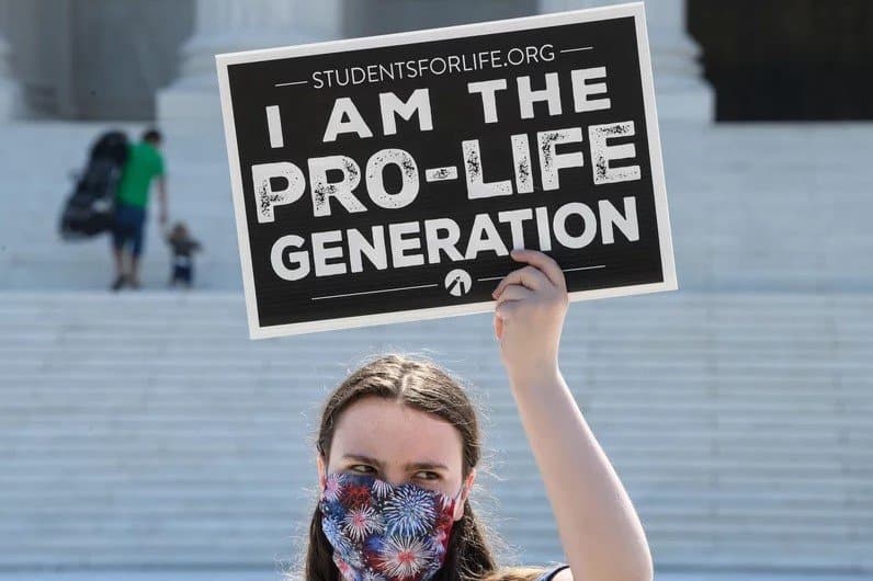 A woman is holding a placard